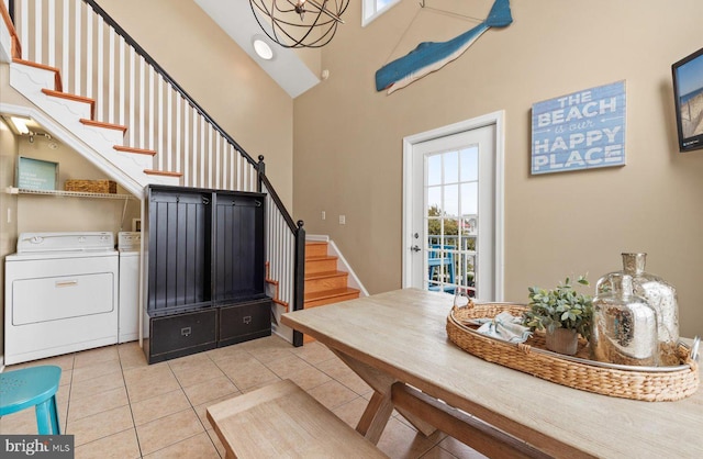 interior space featuring a high ceiling, washing machine and dryer, an inviting chandelier, and light tile patterned floors