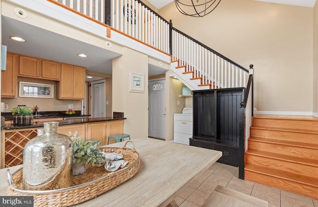 kitchen with washer / dryer, decorative light fixtures, light tile patterned floors, and sink