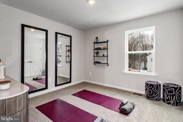 exercise room featuring baseboards, carpet, visible vents, and a healthy amount of sunlight