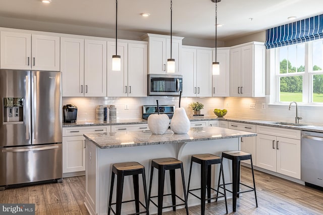 kitchen featuring decorative light fixtures, light stone countertops, white cabinetry, and appliances with stainless steel finishes