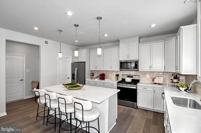 kitchen featuring visible vents, a sink, a kitchen breakfast bar, a kitchen island, and stainless steel appliances