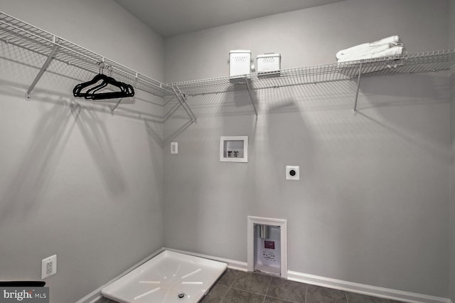laundry area with baseboards, dark tile patterned floors, laundry area, hookup for a washing machine, and electric dryer hookup