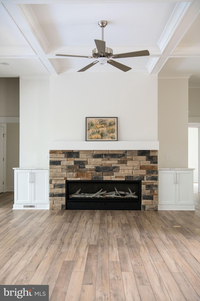 interior details with ceiling fan, coffered ceiling, hardwood / wood-style floors, and a stone fireplace