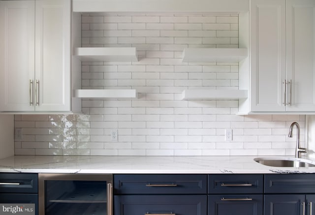 kitchen with decorative backsplash, blue cabinets, white cabinetry, beverage cooler, and sink