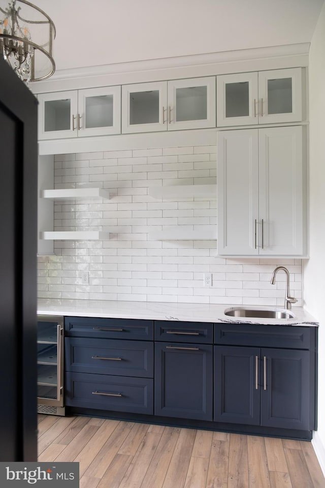 kitchen with white cabinets, light hardwood / wood-style floors, and sink