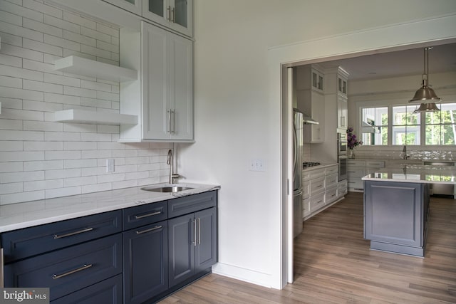 kitchen with white cabinets, light hardwood / wood-style flooring, sink, and decorative backsplash