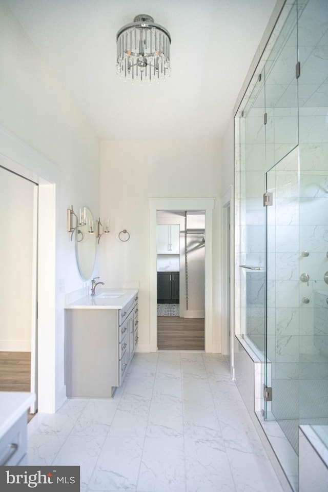 bathroom featuring a notable chandelier, vanity, and a shower with shower door