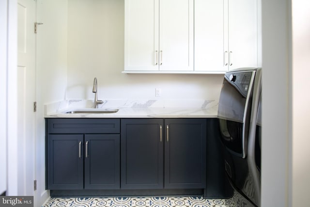 interior space with light stone countertops, white cabinets, washer / dryer, and sink