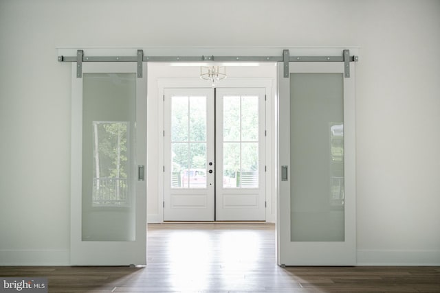 doorway to outside with wood-type flooring, a healthy amount of sunlight, and a barn door