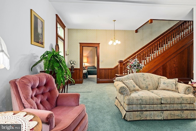 carpeted living room with wallpapered walls, stairway, wainscoting, and a chandelier