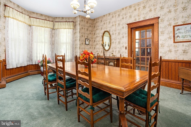 carpeted dining area with a baseboard heating unit, an inviting chandelier, wainscoting, and wallpapered walls