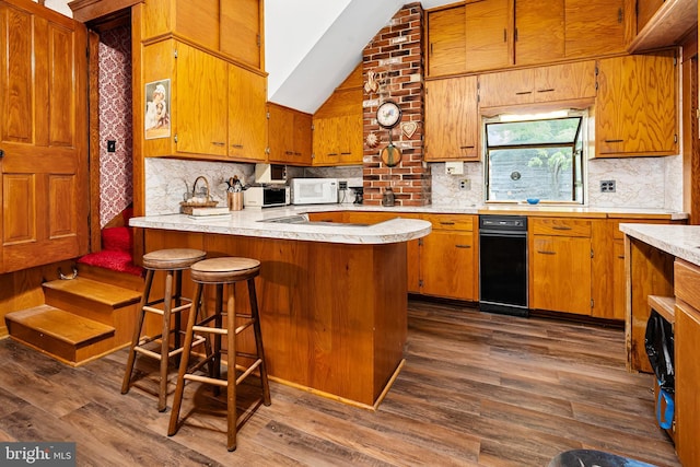 kitchen with dark wood-type flooring, white microwave, brown cabinetry, and light countertops