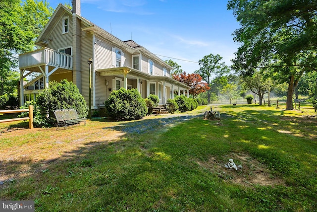 view of side of home with a lawn, a chimney, and fence