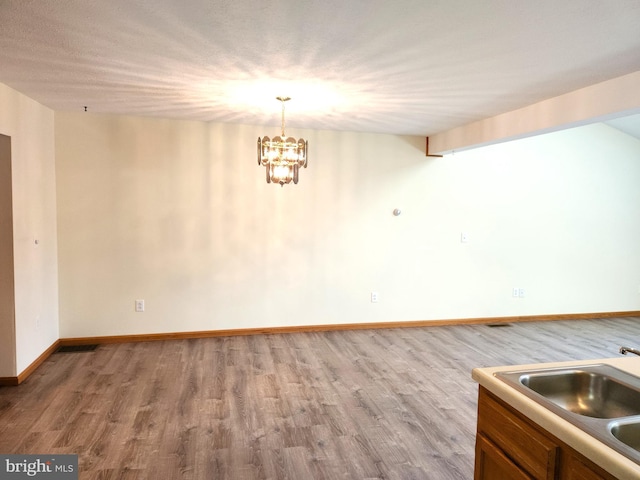 unfurnished dining area featuring light hardwood / wood-style flooring, a notable chandelier, and sink