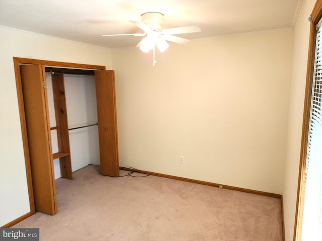 unfurnished bedroom featuring ceiling fan, a closet, light carpet, and crown molding