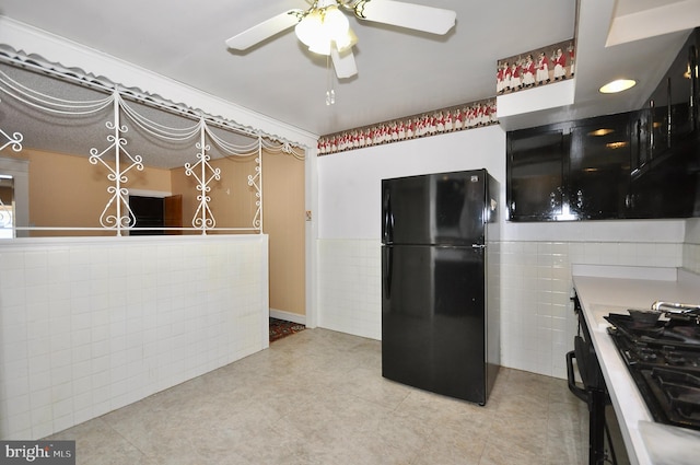 kitchen featuring tile walls, light countertops, wainscoting, ceiling fan, and black appliances