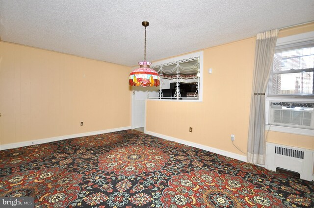 empty room with radiator, cooling unit, a textured ceiling, and carpet flooring