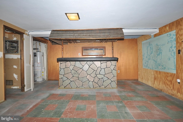 finished basement with a bar, wood walls, and gas water heater