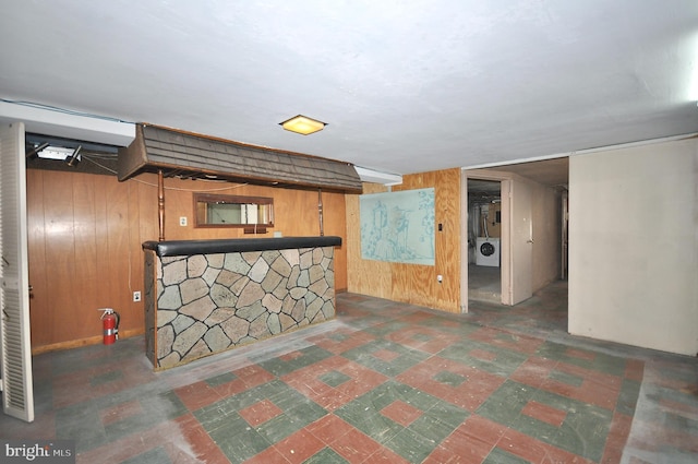 bar with a bar, wooden walls, and washer / clothes dryer