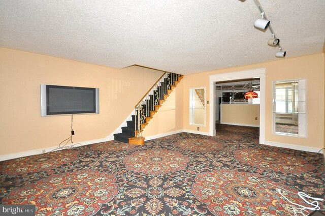 unfurnished living room with track lighting and a textured ceiling