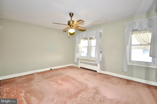 carpeted empty room featuring radiator heating unit, a ceiling fan, and baseboards