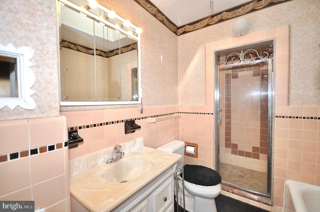 bathroom with a wainscoted wall, tile walls, toilet, vanity, and wallpapered walls