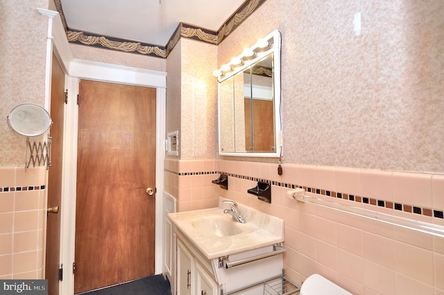 bathroom featuring a wainscoted wall, vanity, and wallpapered walls