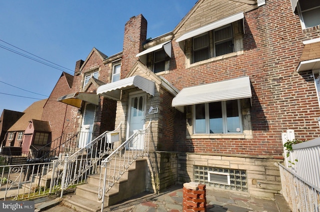 view of front of house featuring stone siding, brick siding, and fence