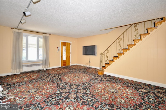 interior space with baseboards, radiator heating unit, rail lighting, stairs, and a textured ceiling