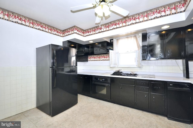 kitchen featuring dark cabinets, light countertops, tile walls, and black appliances