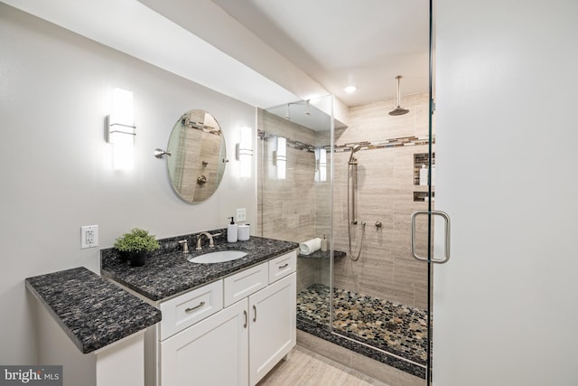 bathroom featuring hardwood / wood-style flooring, walk in shower, and vanity