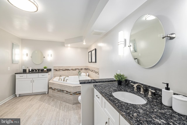 bathroom featuring tiled tub and vanity