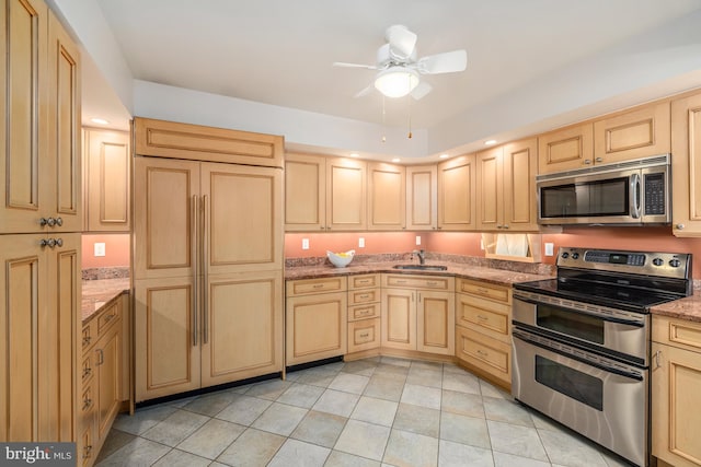 kitchen with appliances with stainless steel finishes, light stone countertops, light brown cabinetry, ceiling fan, and sink