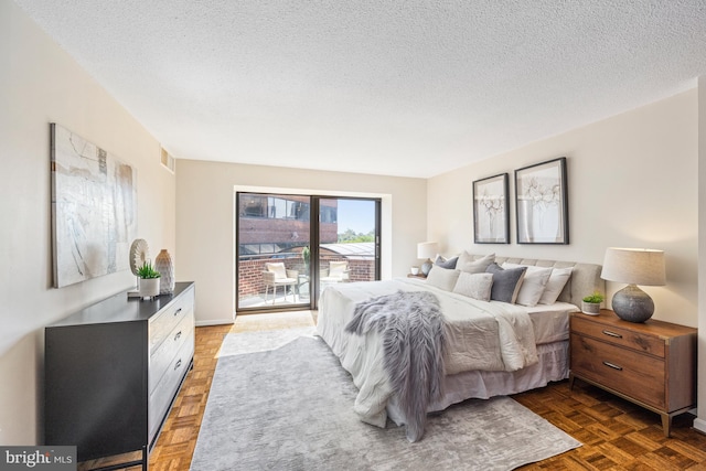 bedroom with a textured ceiling, access to outside, and dark parquet flooring