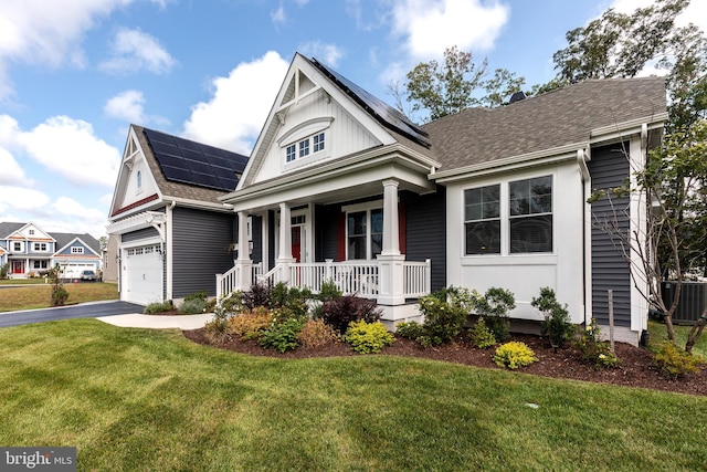 view of front facade with a front lawn, a porch, cooling unit, solar panels, and a garage