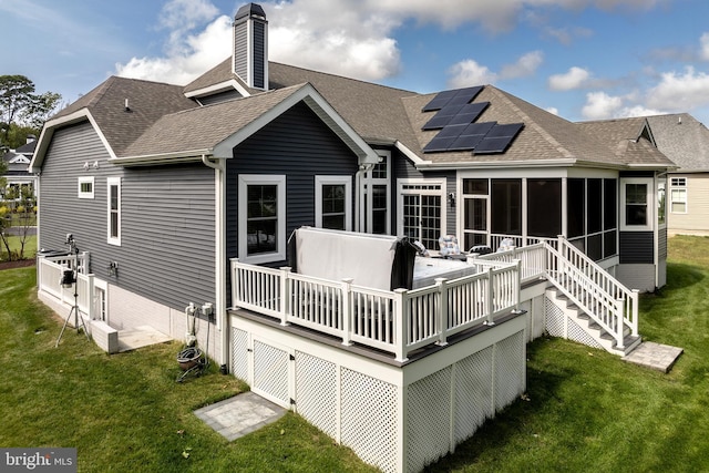 back of house with a deck, a sunroom, and a lawn