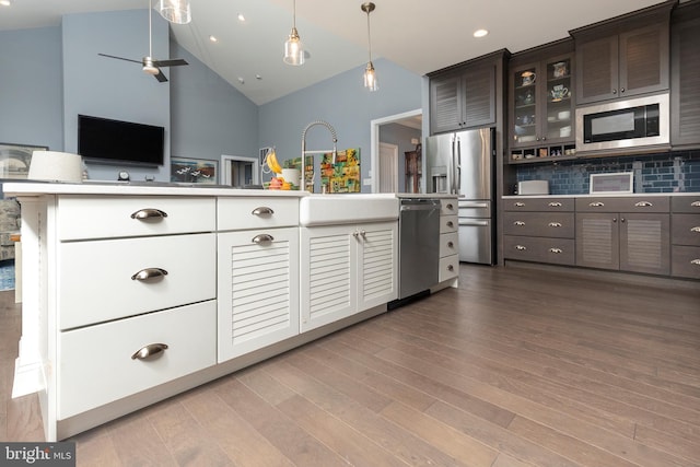 kitchen featuring appliances with stainless steel finishes, light hardwood / wood-style floors, backsplash, pendant lighting, and dark brown cabinets