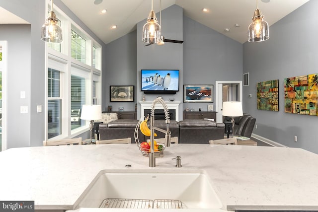 kitchen featuring pendant lighting, high vaulted ceiling, and light stone countertops