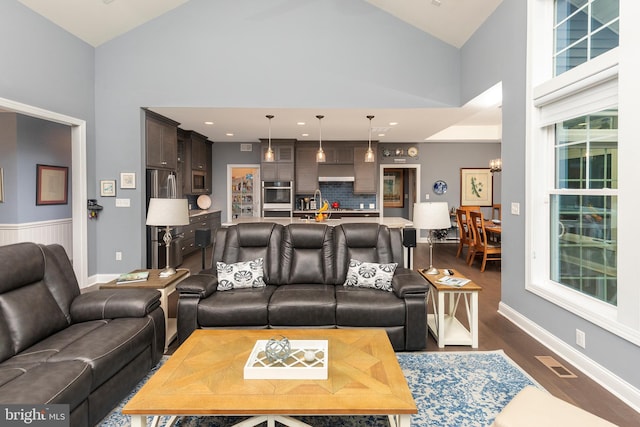 living room with dark wood-type flooring and high vaulted ceiling