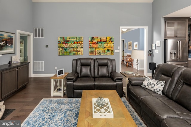 living room featuring dark wood-type flooring and a high ceiling