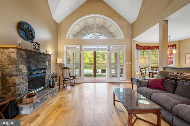 living room featuring high vaulted ceiling, wood-type flooring, and a stone fireplace