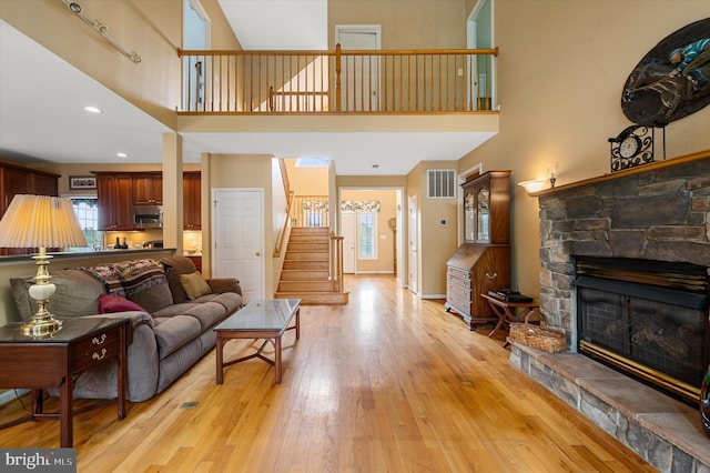 living room featuring a towering ceiling, light hardwood / wood-style floors, and a fireplace