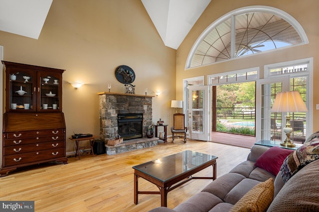 living room featuring a fireplace, high vaulted ceiling, and light hardwood / wood-style flooring