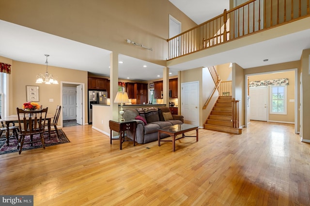 living room with a notable chandelier, light wood-type flooring, and a high ceiling