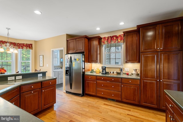 kitchen featuring pendant lighting, stainless steel fridge, light hardwood / wood-style flooring, a chandelier, and washer and dryer