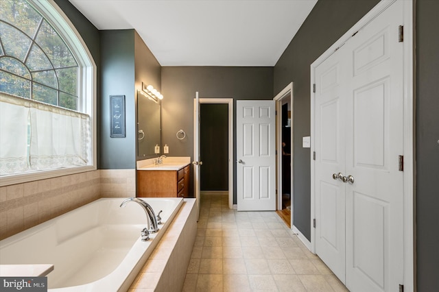 bathroom with tiled tub, vanity, and tile patterned flooring