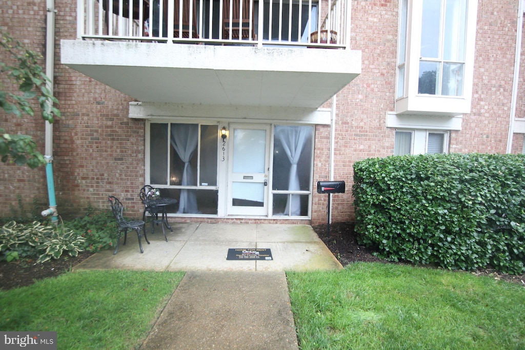 view of exterior entry with a patio and a balcony