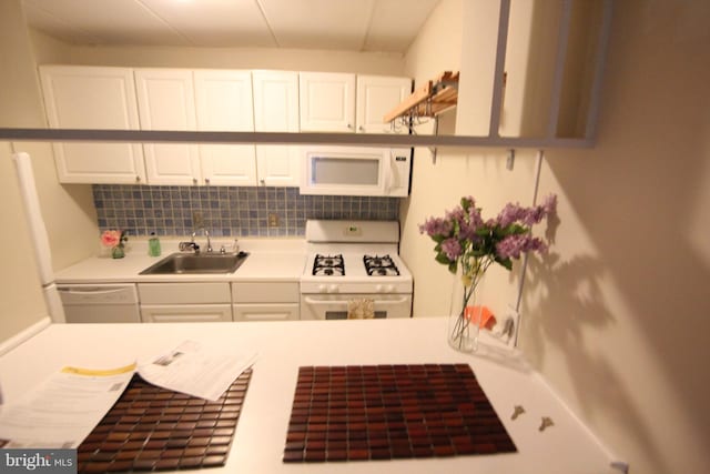 kitchen featuring sink, white appliances, white cabinets, and backsplash