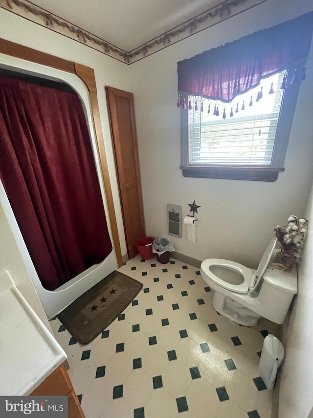 bathroom featuring heating unit and toilet