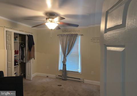 bedroom with carpet flooring, ornamental molding, ceiling fan, and a closet